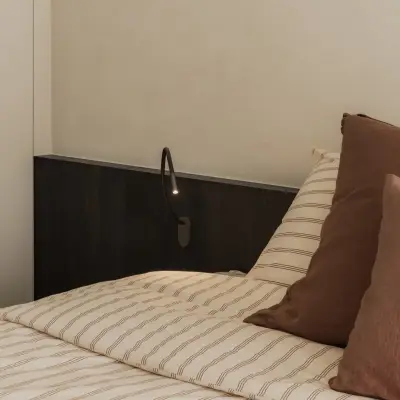 Hoek van het bed met hoofdbord, leeslamp en kussens, Appartement in Nieuwpoort, interieur Laura Calleeuw
