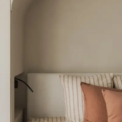 Het bed in de boogvormige nis met gestreept beddengoed en kussens, Appartement in Nieuwpoort, interieur Laura Calleeuw
