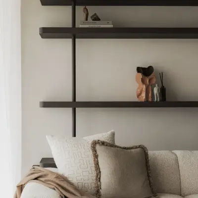 Planken met vazen en boeken boven een sofa met kussens, Appartement in Nieuwpoort, interieur Laura Calleeuw