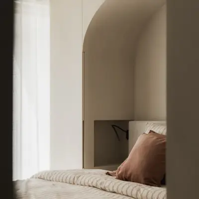 Slaapkamer met boogvormige nis, bed en spiegeling in de wand, Appartement in Nieuwpoort, interieur Laura Calleeuw