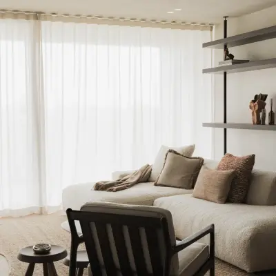Sofa en fauteuil in de zithoek voor open rekken en vitrage, Appartement in Nieuwpoort, interieur Laura Calleeuw