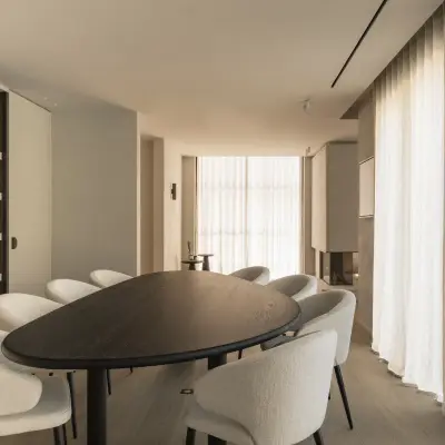 Eetkamer met ovale donkere tafel, ronde stoelen en een verlichte kast met ribbelwand, Gezinsvilla in Heusden-Zolder, interieur Laura Calleeuw