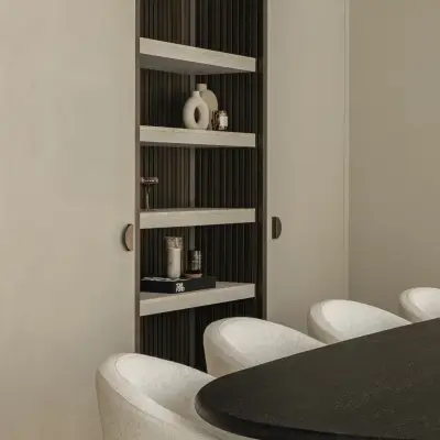 Ovale eettafel met stoelen naast de verlichte kastnis, Gezinsvilla in Heusden-Zolder, interieur Laura Calleeuw