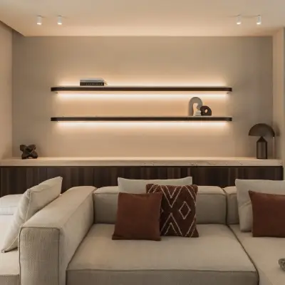 Hoeksofa met terracotta kussens voor een houten kast met verlichte wandplanken, Gezinsvilla in Heusden-Zolder, interieur Laura Calleeuw