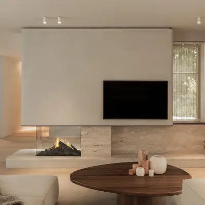 Leefruimte met televisie boven een open haard in natuursteen en een ovale houten salontafel, Gezinsvilla in Heusden-Zolder, interieur Laura Calleeuw