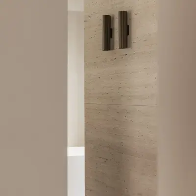Bronzen wandlamp tegen een travertijnen wand, Gezinsvilla in Heusden-Zolder, interieur Laura Calleeuw