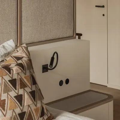 Hoek van het bed met gestoffeerd hoofdbord, leeslamp en kussen, Hoeve in Westkapelle, interieur Laura Calleeuw