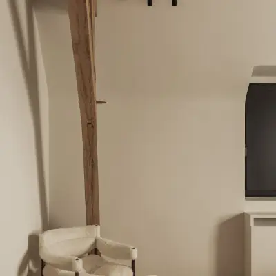 Fauteuil met schapenvacht en poef onder een houten gordingbalk, Hoeve in Westkapelle, interieur Laura Calleeuw