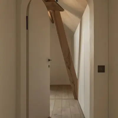 Gang met witte boogdeur en een houten balk, Hoeve in Westkapelle, interieur Laura Calleeuw