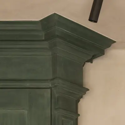 Detail van het lijstwerk op de groen geschilderde kast naast een zwarte spot, Hoeve in Westkapelle, interieur Laura Calleeuw