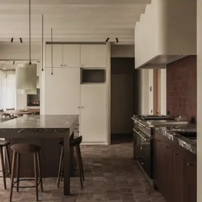Keuken met kookeiland met zitplaatsen, rode tegels en een lichtgroene hanglamp, Hoeve in Westkapelle, interieur Laura Calleeuw