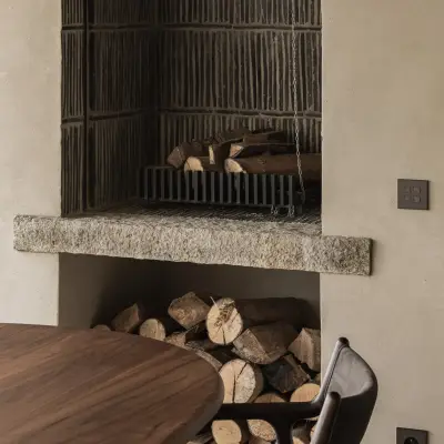 Open haard met zwarte ribbelwand, houtstapel en een granieten latei, Hoeve in Westkapelle, interieur Laura Calleeuw