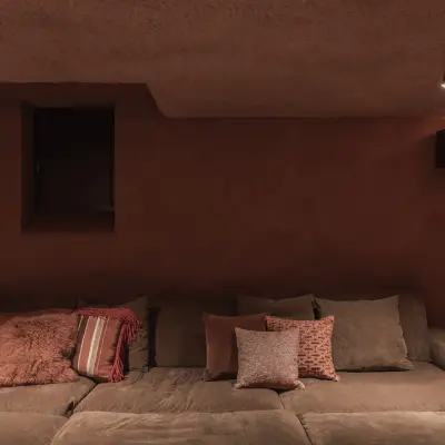 Thuisbioscoop met brede zetel, kussens, schapenvacht en ingebouwde luidsprekers, Hoeve in Westkapelle, interieur Laura Calleeuw