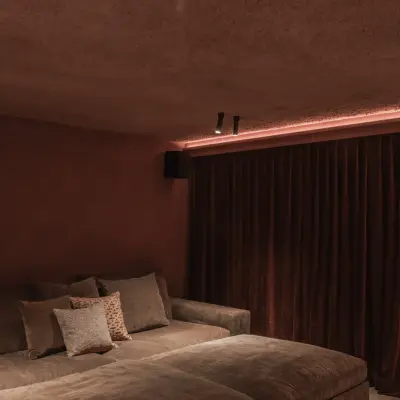 Brede zetel met kussens voor een fluwelen gordijn in de thuisbioscoop, Hoeve in Westkapelle, interieur Laura Calleeuw
