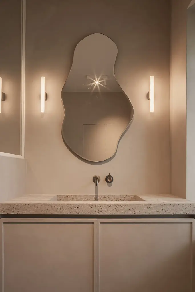 Golvende spiegel boven de natuurstenen wastafel met wandlampen, met en zonder verlichting, centuries of elegance, thoughtfully reimagined for today, interieur Laura Calleeuw
