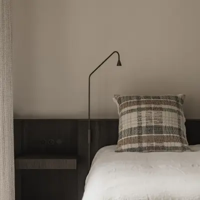 Bed met leeslamp en geruit sierkussen tegen donker eiken hoofdeinde, Schuur in Westkapelle, interieur Laura Calleeuw