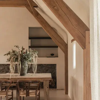 Lange eiktafel onder de eikenhouten spanten met vaas met takken, Schuur in Westkapelle, interieur Laura Calleeuw