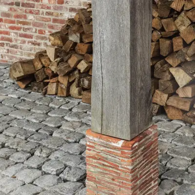 Eikenhouten paal op bakstenen voet met kasseien en gestapeld brandhout, Schuur in Westkapelle, interieur Laura Calleeuw