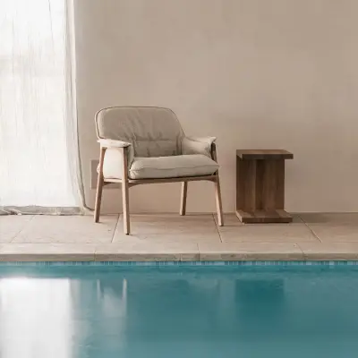 Zithoek met fauteuils en houten bijzettafel naast het zwembad, Schuur in Westkapelle, interieur Laura Calleeuw
