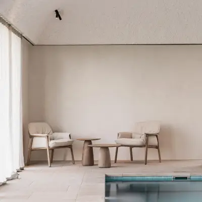 Zithoek met fauteuils en houten bijzettafel naast het zwembad, Schuur in Westkapelle, interieur Laura Calleeuw