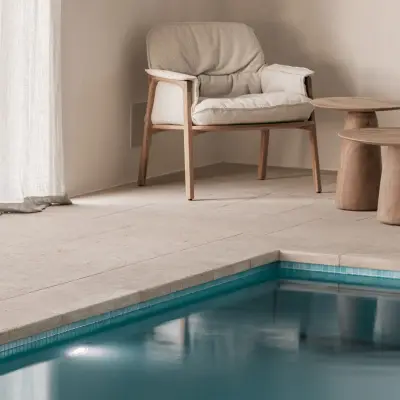 Zithoek met fauteuils en houten bijzettafel naast het zwembad, Schuur in Westkapelle, interieur Laura Calleeuw