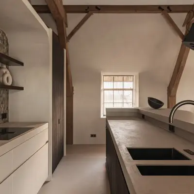 Keukeneiland met dubbele spoelbak en kookplaat onder eikenhouten spanten, Schuur in Westkapelle, interieur Laura Calleeuw
