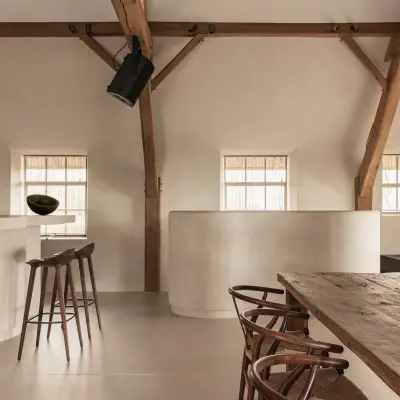 Keuken en eethoek met eikenhouten tafel en wishbone stoelen onder de spanten, Schuur in Westkapelle, interieur Laura Calleeuw
