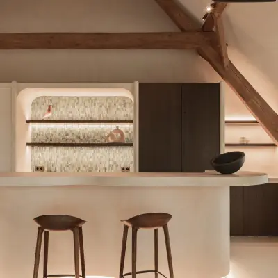 Keukeneiland met barkrukken voor een nis met verlichte planken en tegelrugwand, Schuur in Westkapelle, interieur Laura Calleeuw