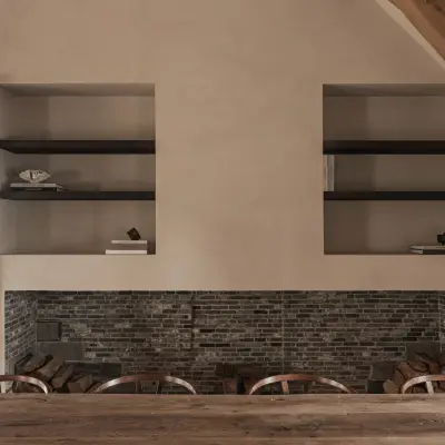 Bakstenen haard met twee nissen met verlichte planken boven een eikenhouten tafel, Schuur in Westkapelle, interieur Laura Calleeuw