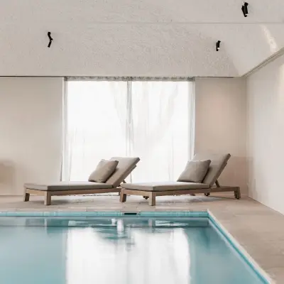 Zwembad met ligstoelen, fauteuils en rolluik over het water, Schuur in Westkapelle, interieur Laura Calleeuw